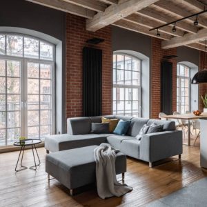 Industrial interior with gray corner sofa and big windows and brick wall